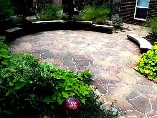 a circular patio with a bench in the middle of it and a brick wall surrounding it .