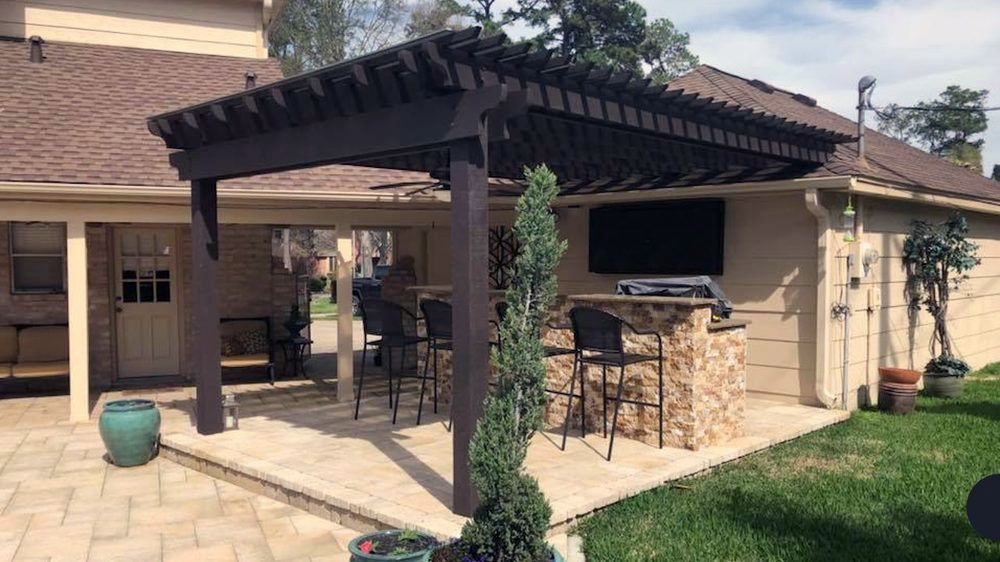 Custom outdoor kitchen covered by a dark cedar pergola