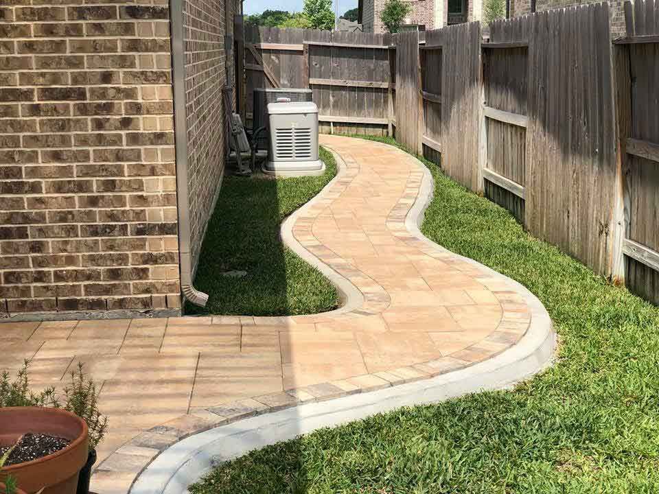 Clear pavers pathway in the side of a house with grass
