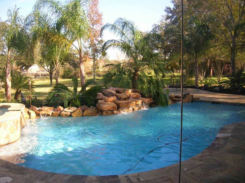 Pool with stone waterfall fountain and landscaping of tree palms