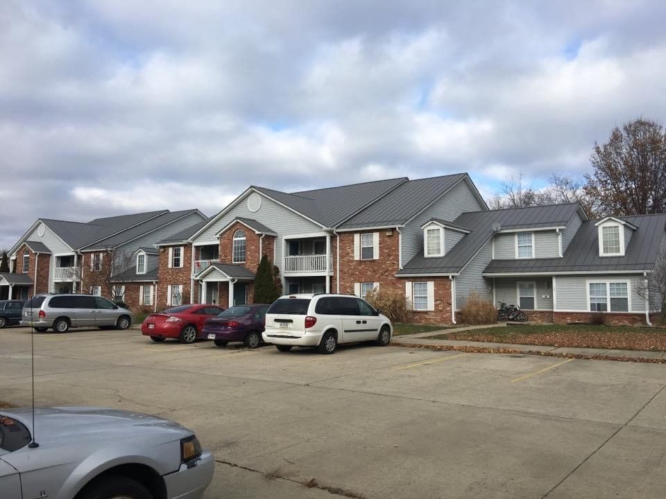 Suburban apartment buildings with parked cars under a cloudy sky