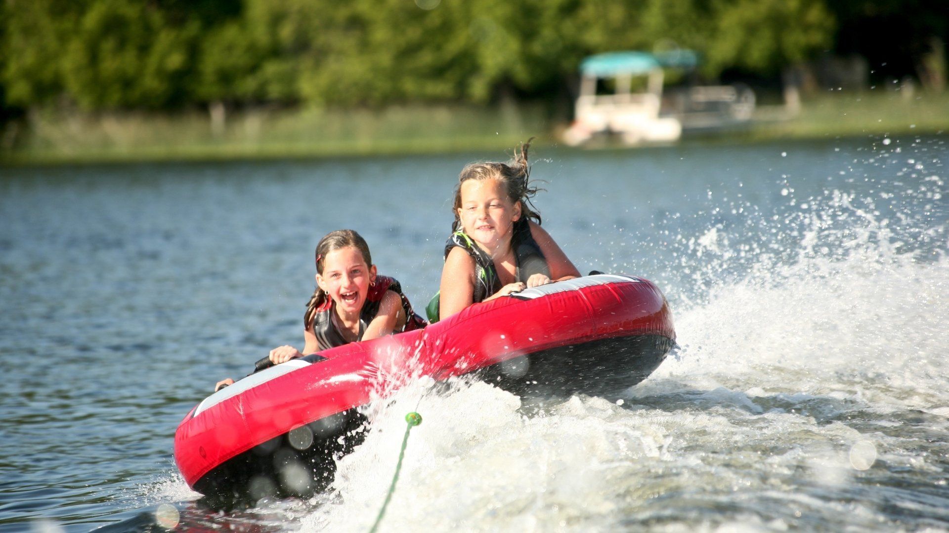 two children on inner tube being pulled by boat