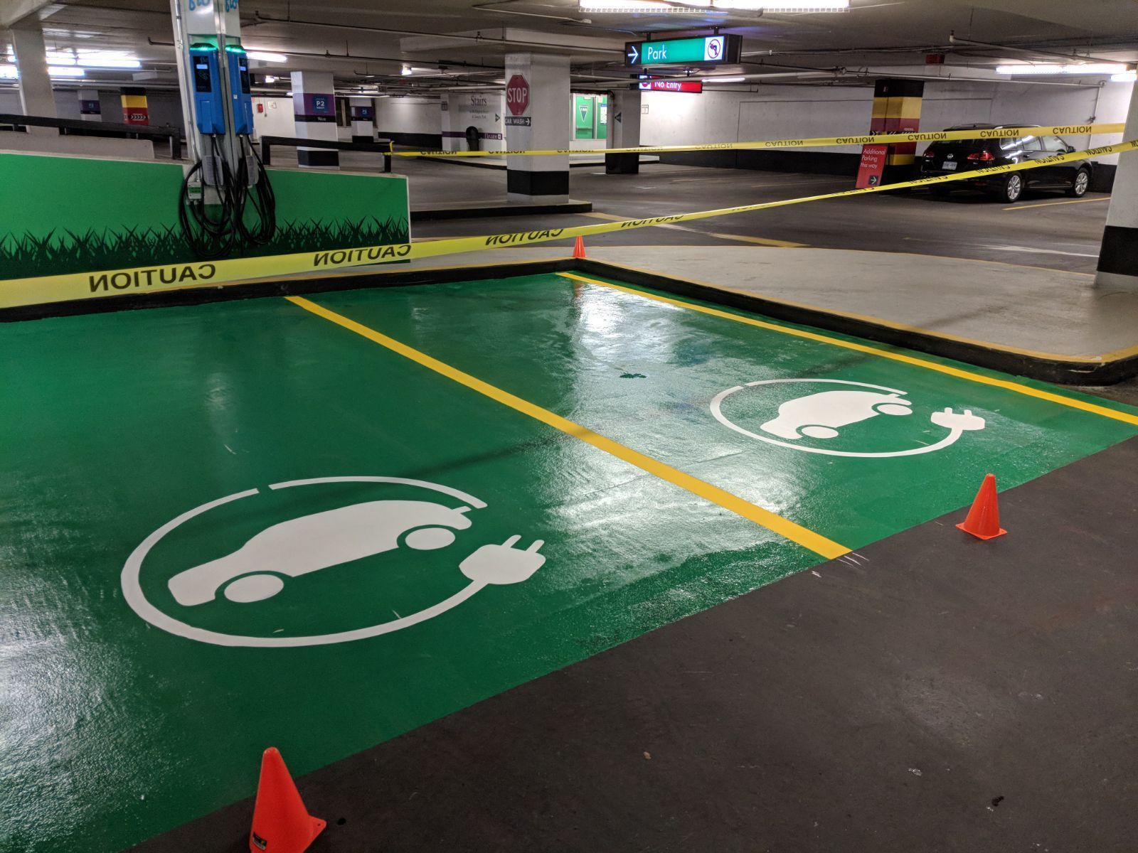 Electric vehicle charging station in a parking garage. Green painted surface with car symbols.
