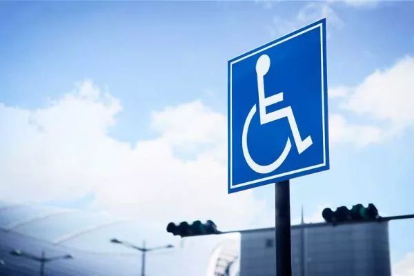 Blue handicap parking sign against a cloudy sky.