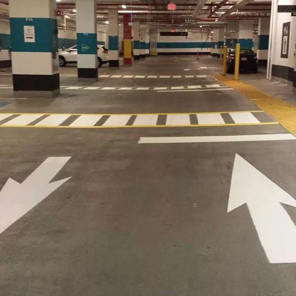 Parking garage with painted arrows and crosswalk markings on the concrete floor.