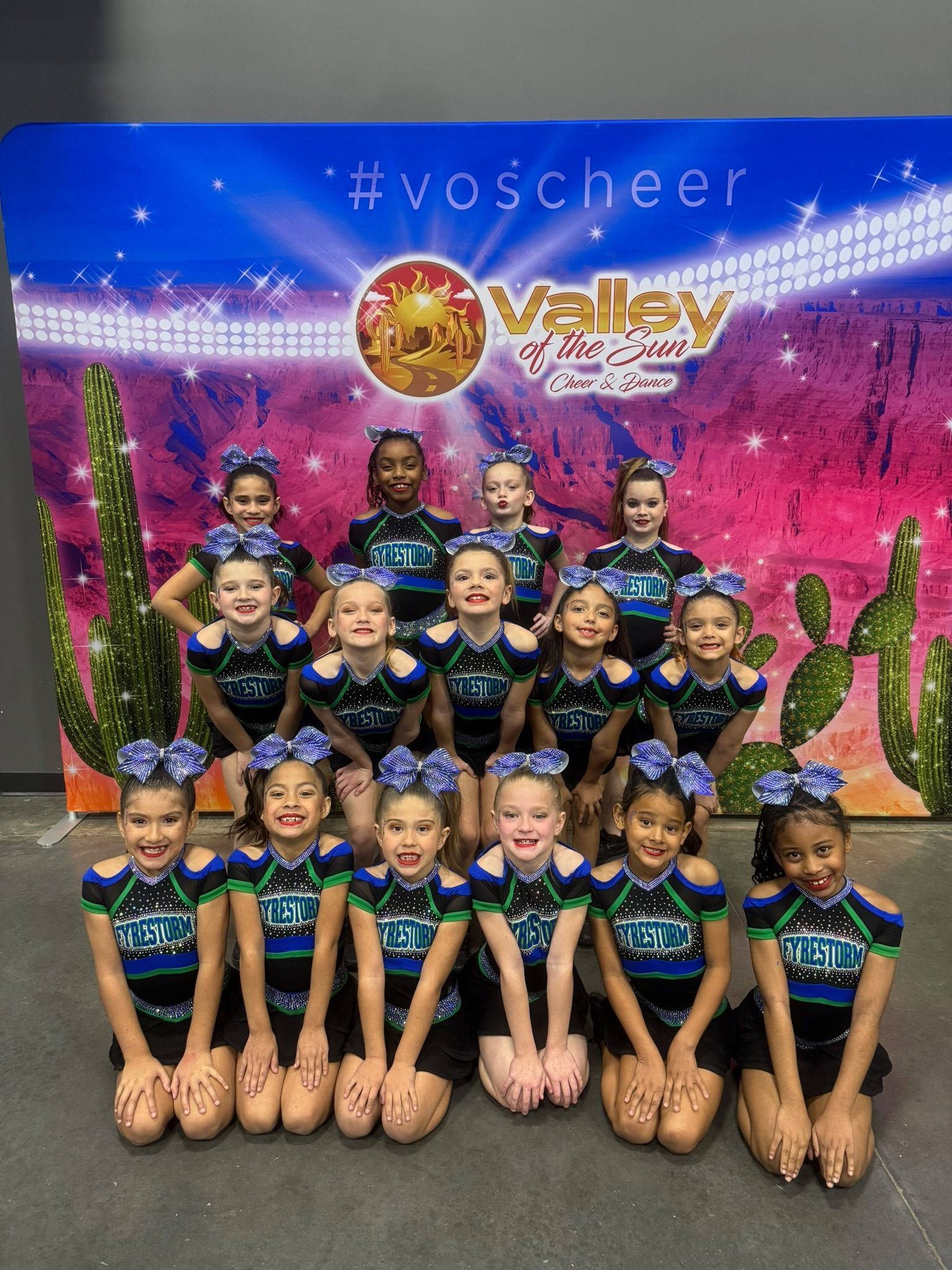 Cheer team posing in uniform against a colorful Valley backdrop