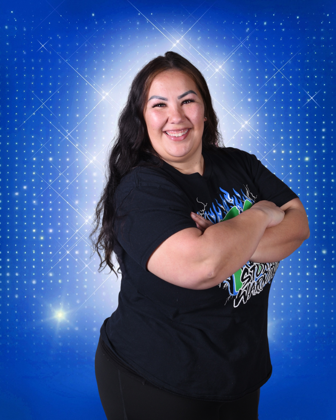 Smiling woman with crossed arms in a black T-shirt against a blue starry backdrop