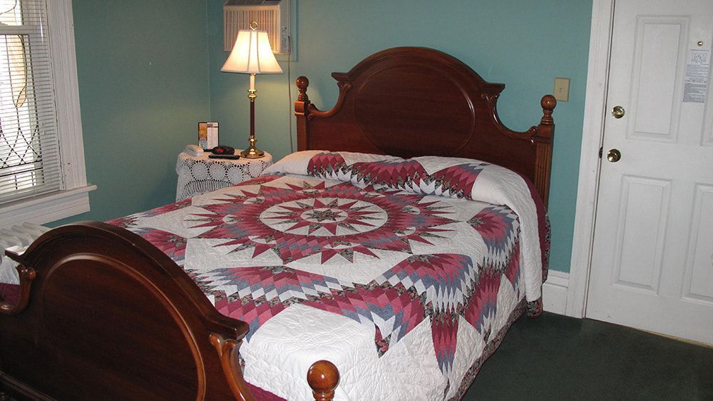 A bed with a red and white quilt in a bedroom