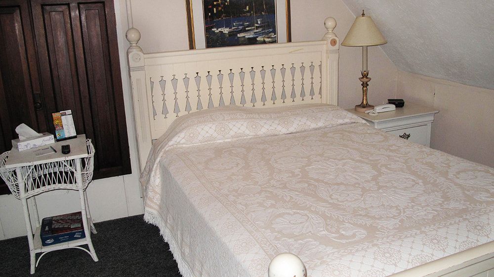 A bedroom with a bed a nightstand and a lamp