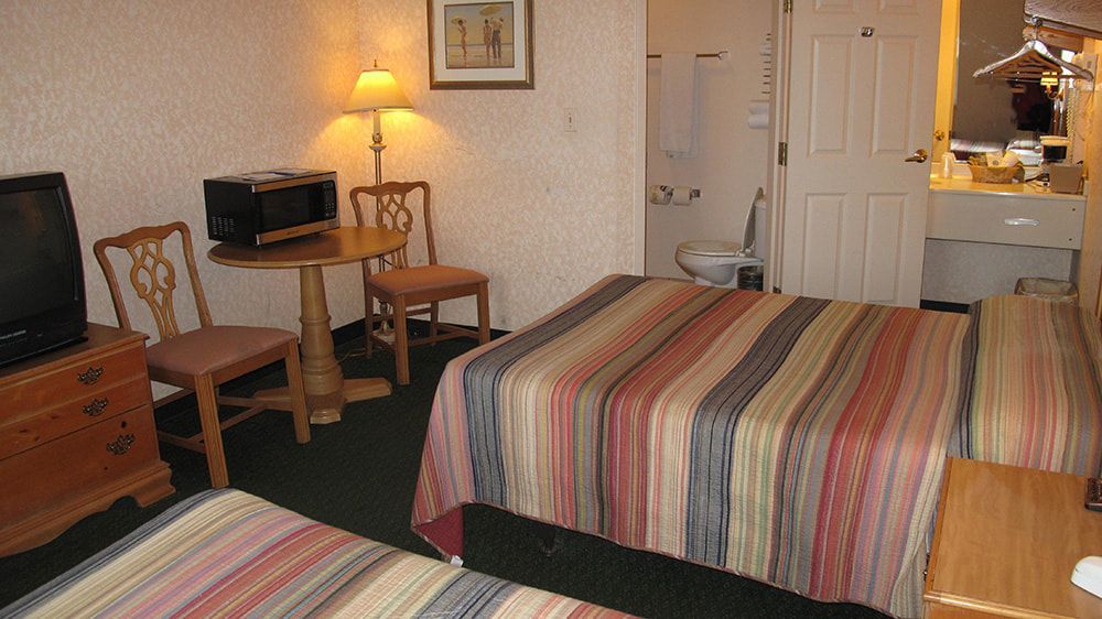 A hotel room with two beds and a television