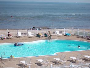 People are swimming in a large swimming pool near the ocean