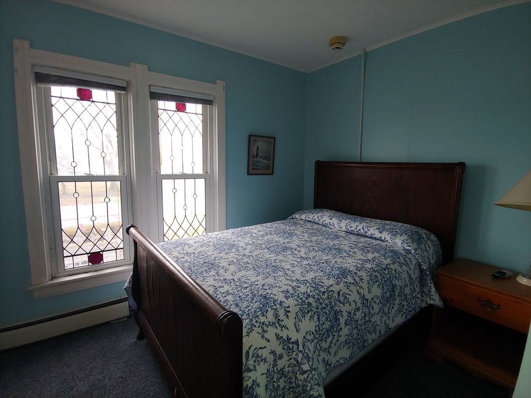 A bedroom with a bed and two windows with stained glass