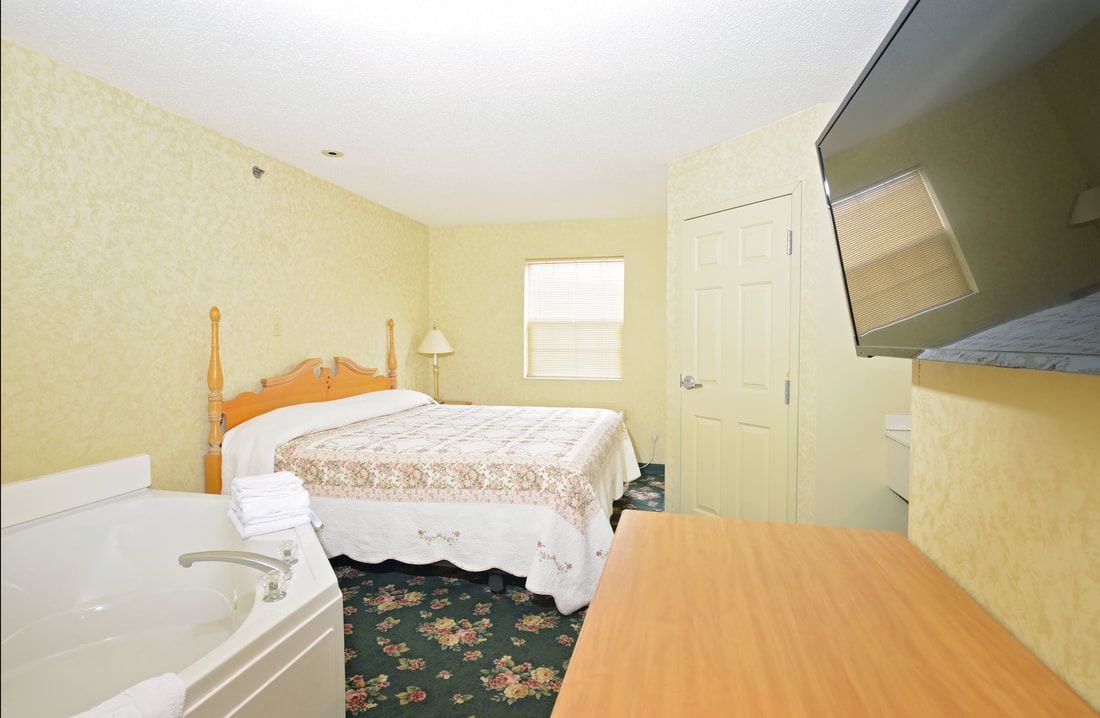 A hotel room with a bed and a jacuzzi tub.