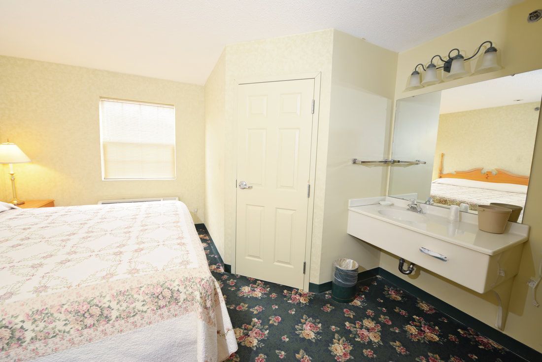 A hotel room with a bed , sink and mirror