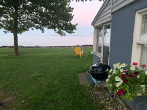 A barbecue grill is sitting in front of a house with a view of the ocean.