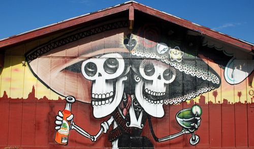A painting of a skeleton wearing a sombrero holding a drink