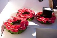 Red floral wreaths on a white surface, with one open black box beside them.