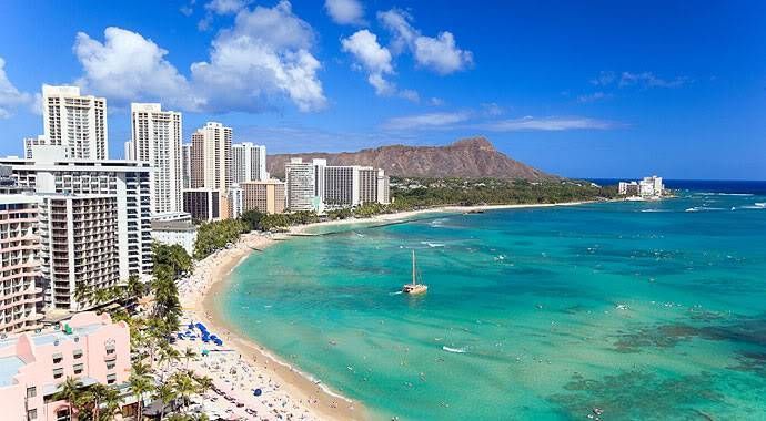 Waikiki Beach with turquoise water, white high-rises, and Diamond Head under a blue sky