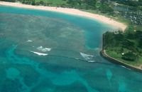 Aerial view of a turquoise tropical bay with a sandy beach and green shoreline