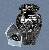 A broken black ceramic jar with a detached lid, showing a spring inside, against a gray background