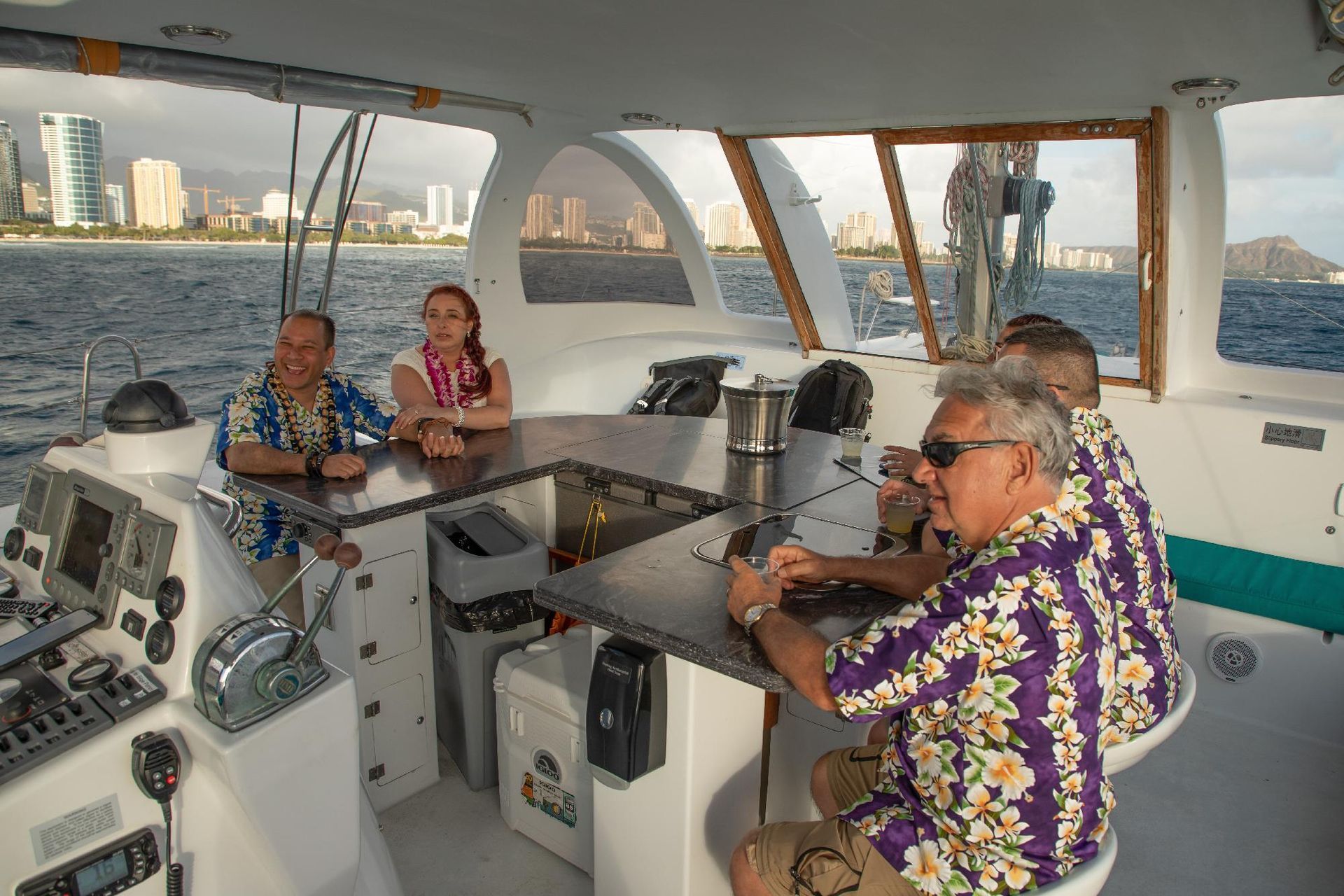 People relaxing inside a yacht cabin with a city skyline visible through the windows.