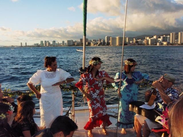 People dancing on a boat with a city skyline and water in the background.
