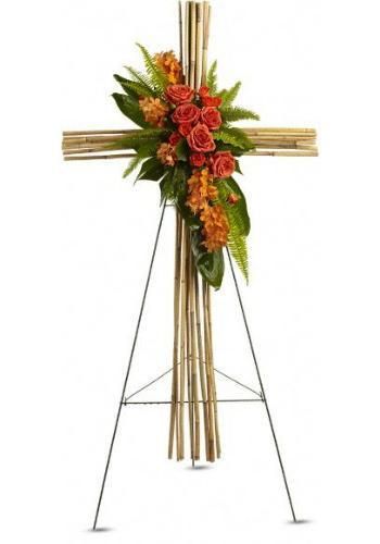 Floral arrangement on a wooden cross stand with red and orange flowers and green leaves
