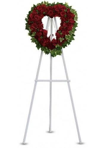 Red floral funeral wreath on a white metal easel stand