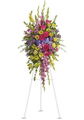 Colorful floral spray on a white easel stand with pink, purple, yellow, and red flowers