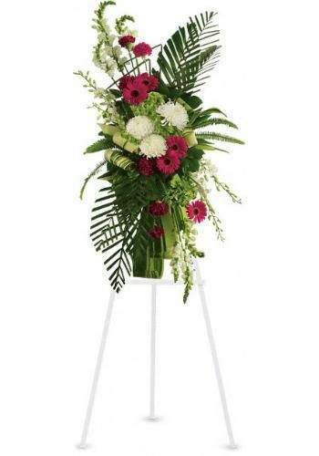 Tall floral arrangement with red and white flowers and greenery on a white tripod stand