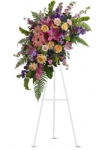 Large pink, purple, and yellow floral wreath on a white easel stand