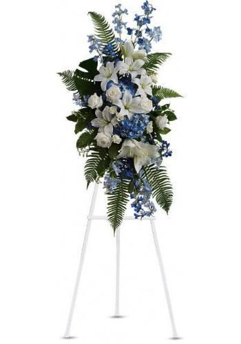 White and blue floral funeral spray on a white easel stand