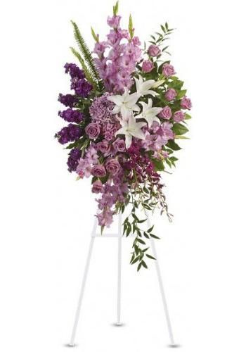 Tall floral arrangement on a white stand with purple, pink, and white flowers and green foliage