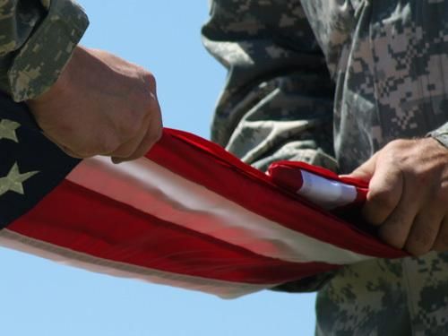 Hands in military uniforms folding an American flag.