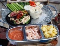 Assorted raw seafood and vegetables arranged on a tabletop platter, ready for cooking