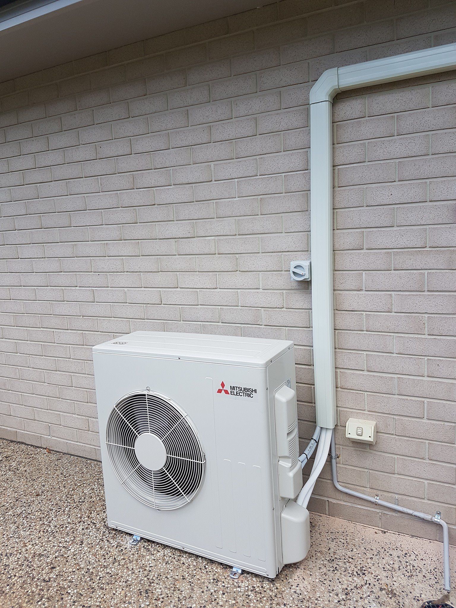 White Air Conditioner Is Sitting On The Side Of A Brick Building โ Stand Fast Electrical Pty Ltd in Warwick, QLD