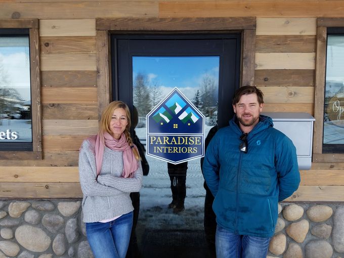 A man and a woman are standing in front of paradise interiors