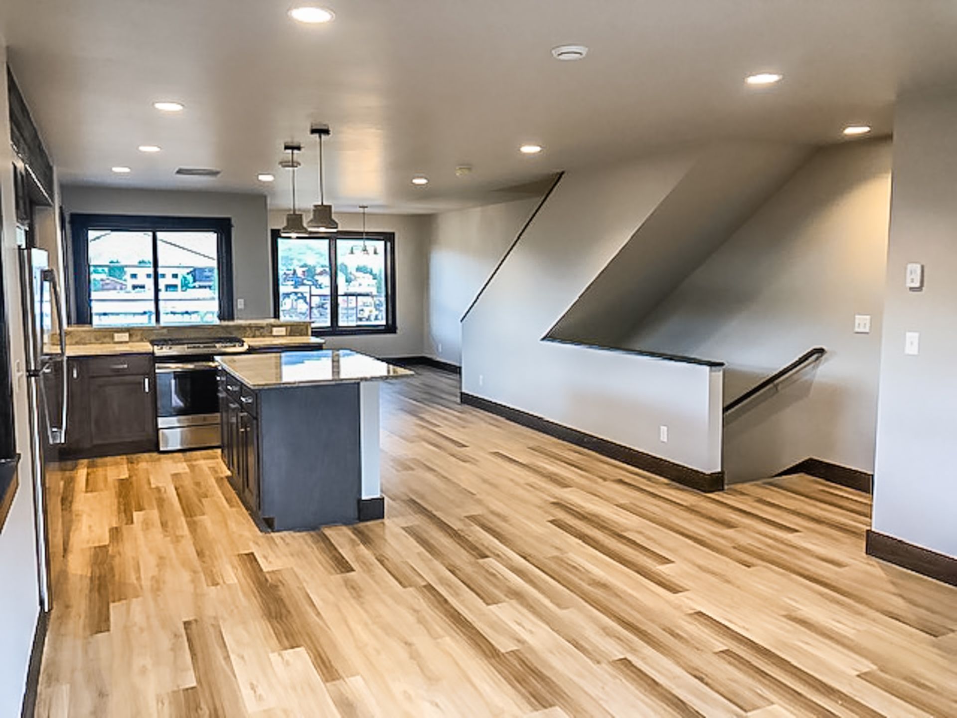 An empty kitchen with hardwood floors and a staircase leading to the second floor.
