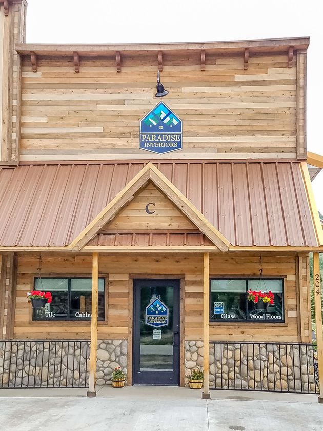 The front of a wooden building with a metal roof and a sign on it.