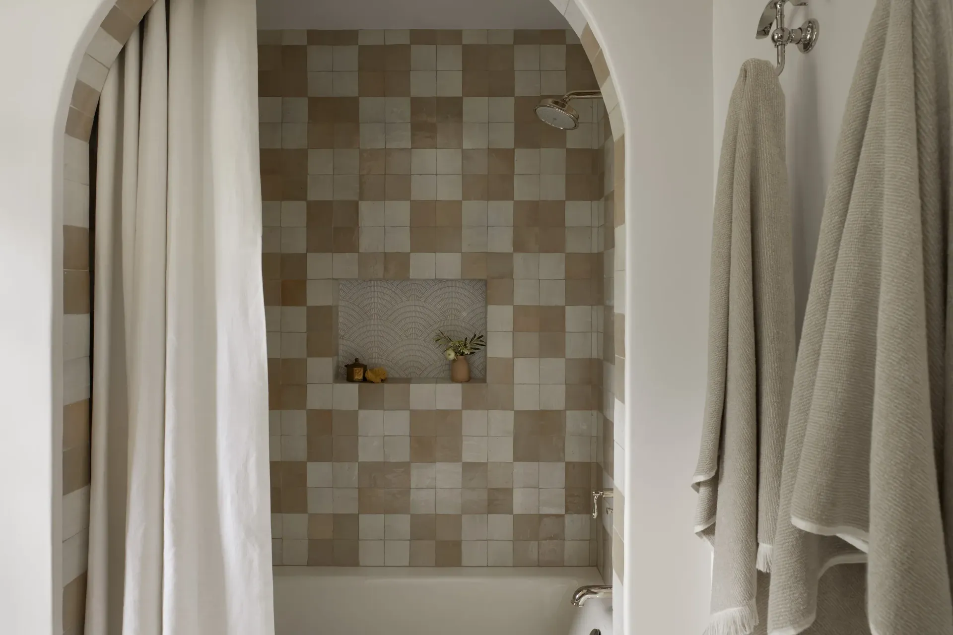 A bathroom with a tub , shower , and towels hanging on the wall.