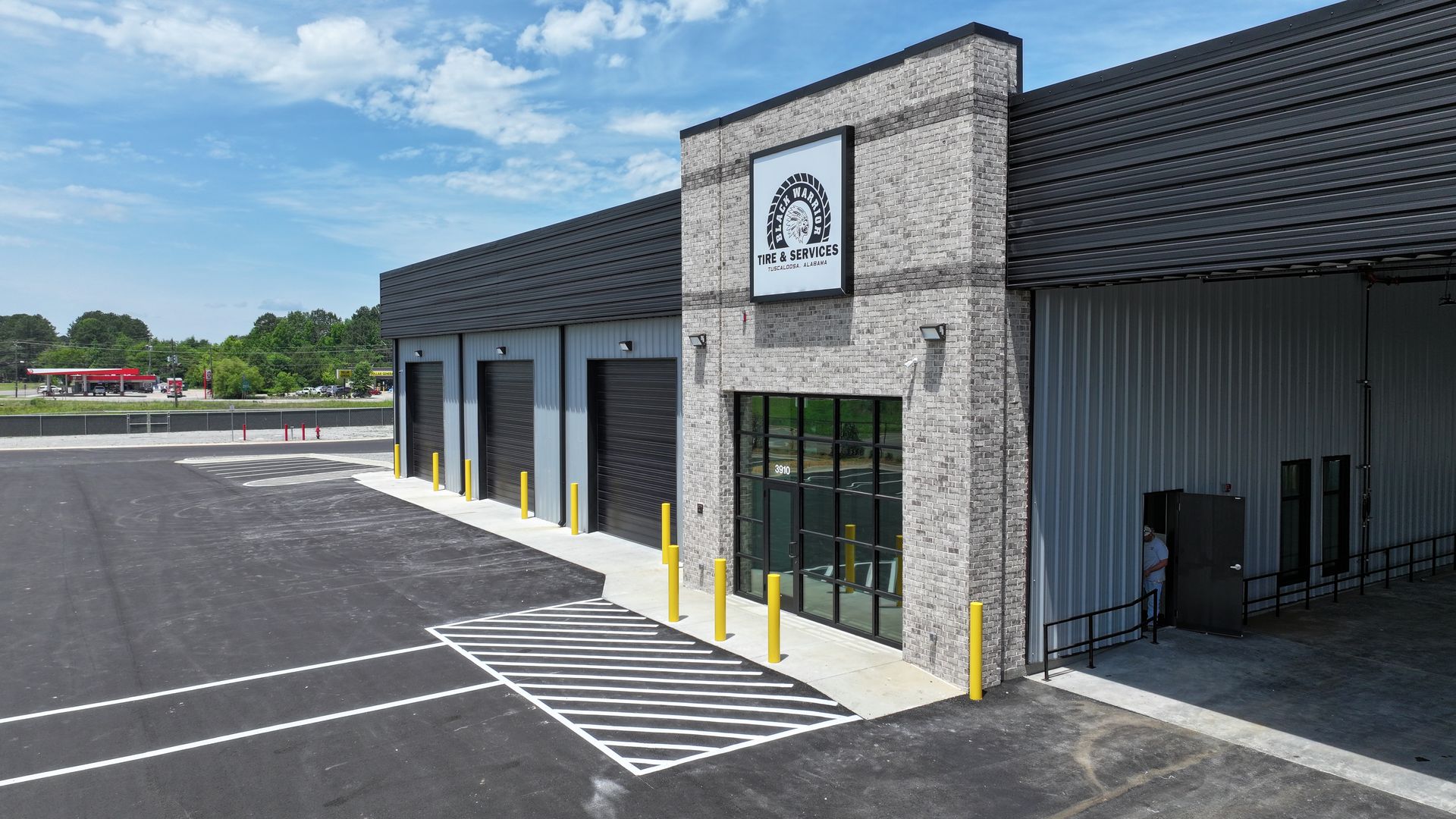 Modern commercial building exterior with black facade, glass entrance, and empty parking lot