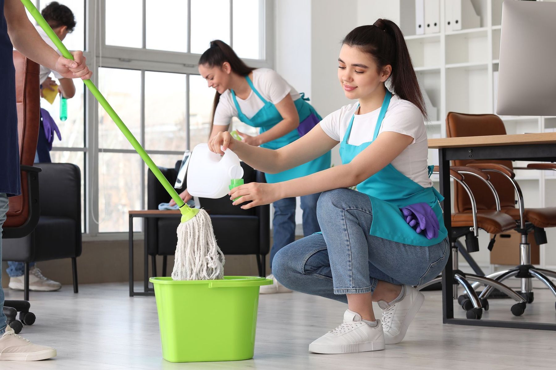 A group of people are cleaning an office with mop and bucket.