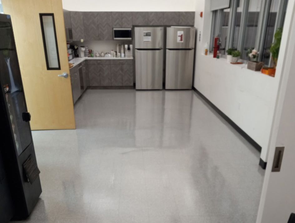 A kitchen with two stainless steel refrigerators and a vending machine