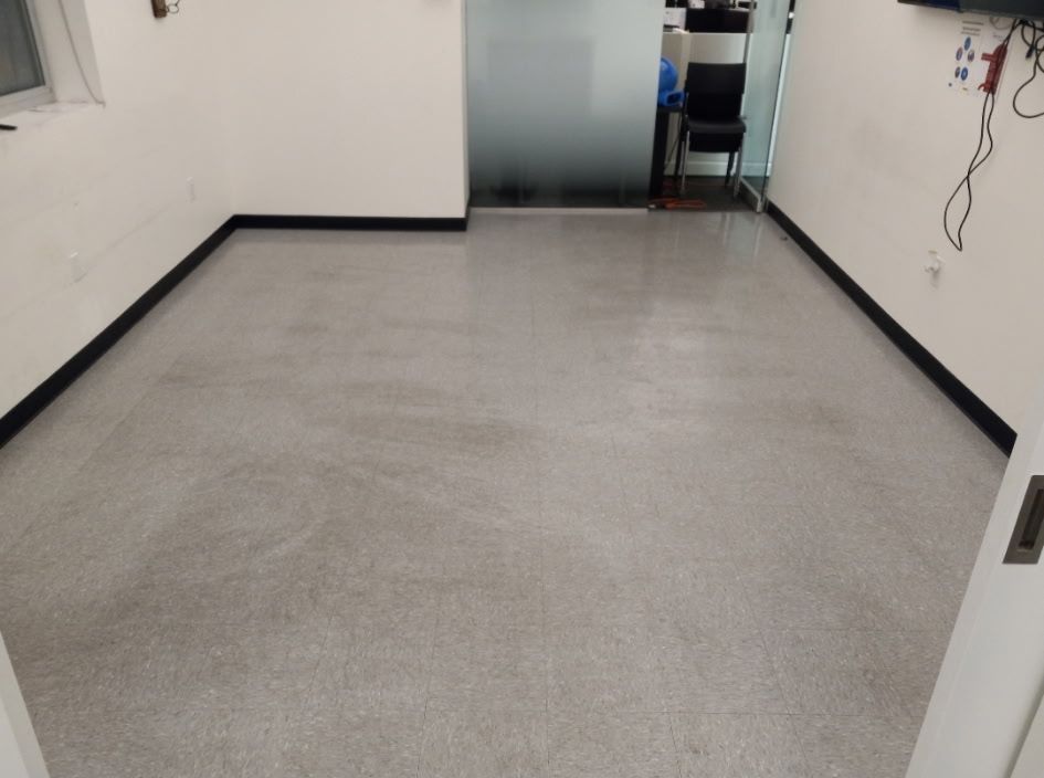 An empty room with a gray floor and white walls