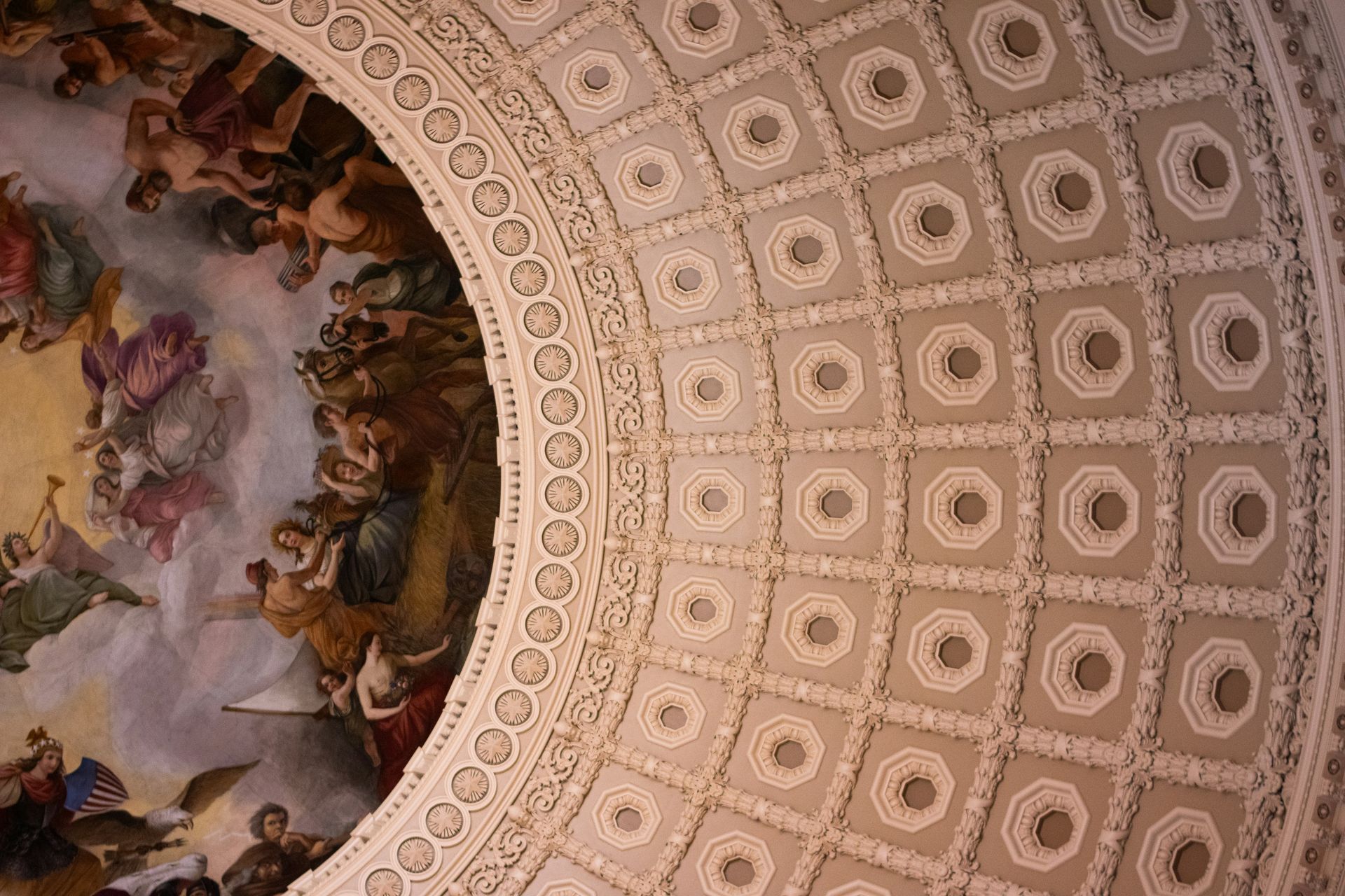 Ceiling of the U.S. Capitol dome featuring ornate sculpted details and a mural of figures in the sky.