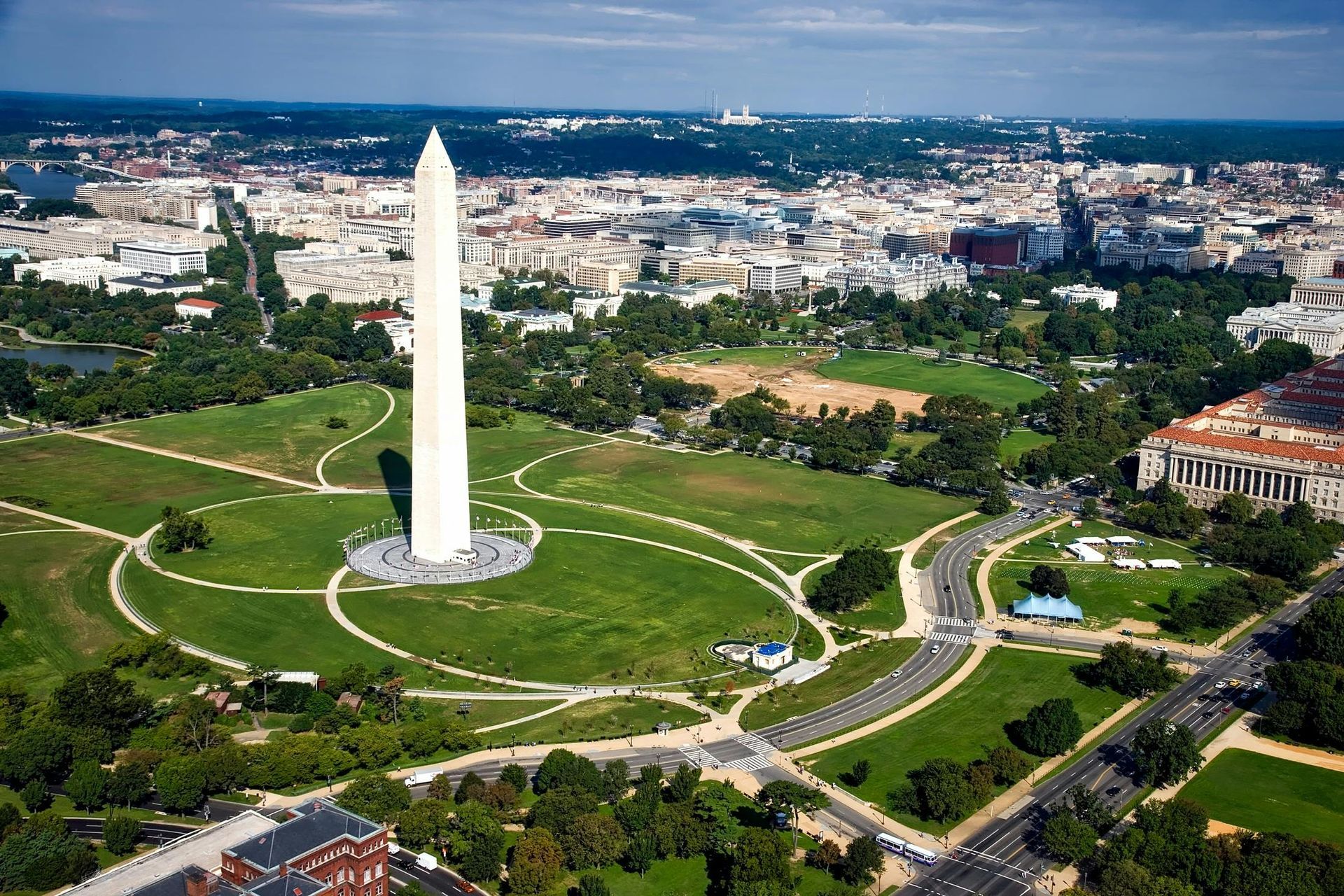 Washington Monument in Washington, D.C., with green park and cityscape in background.