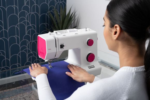 A woman is using a sewing machine to sew a piece of fabric.