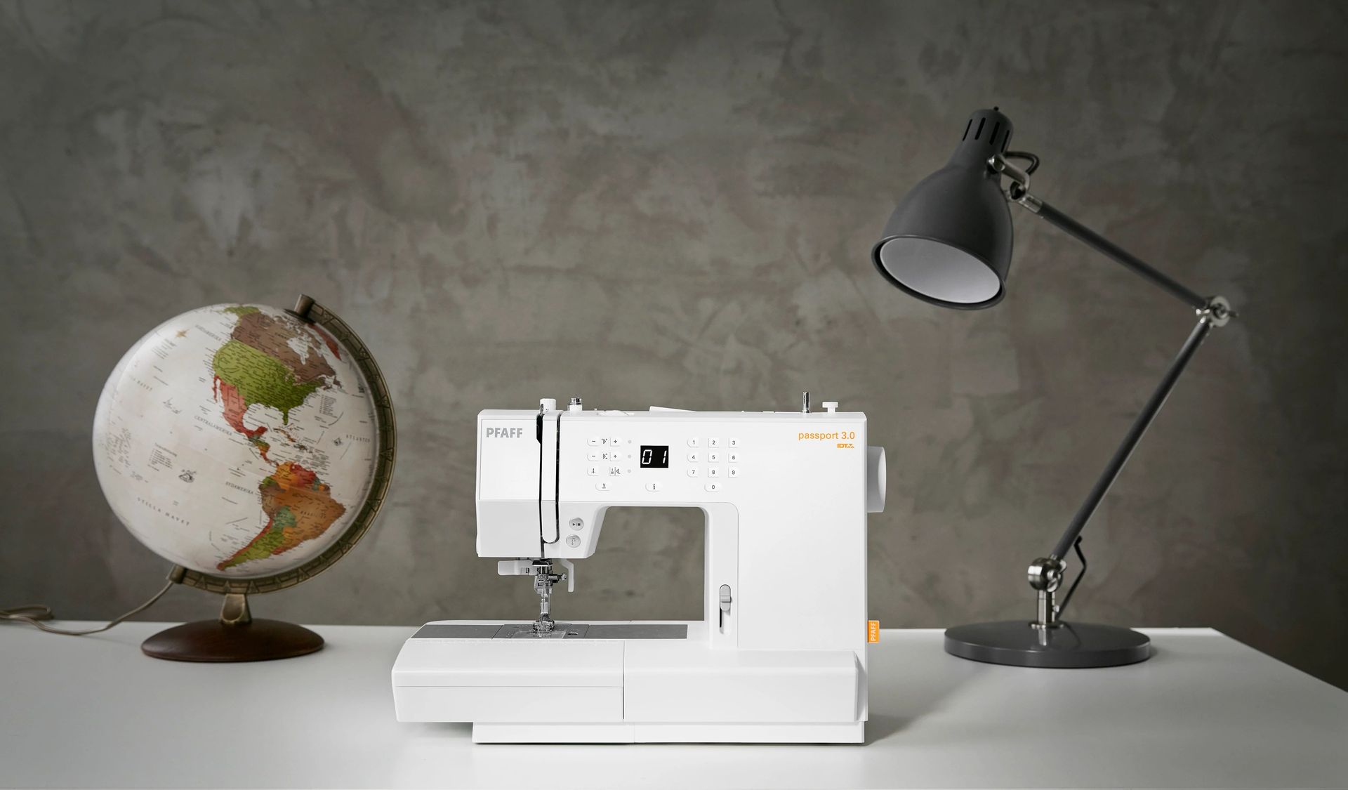 A sewing machine is sitting on a table next to a lamp and a globe.