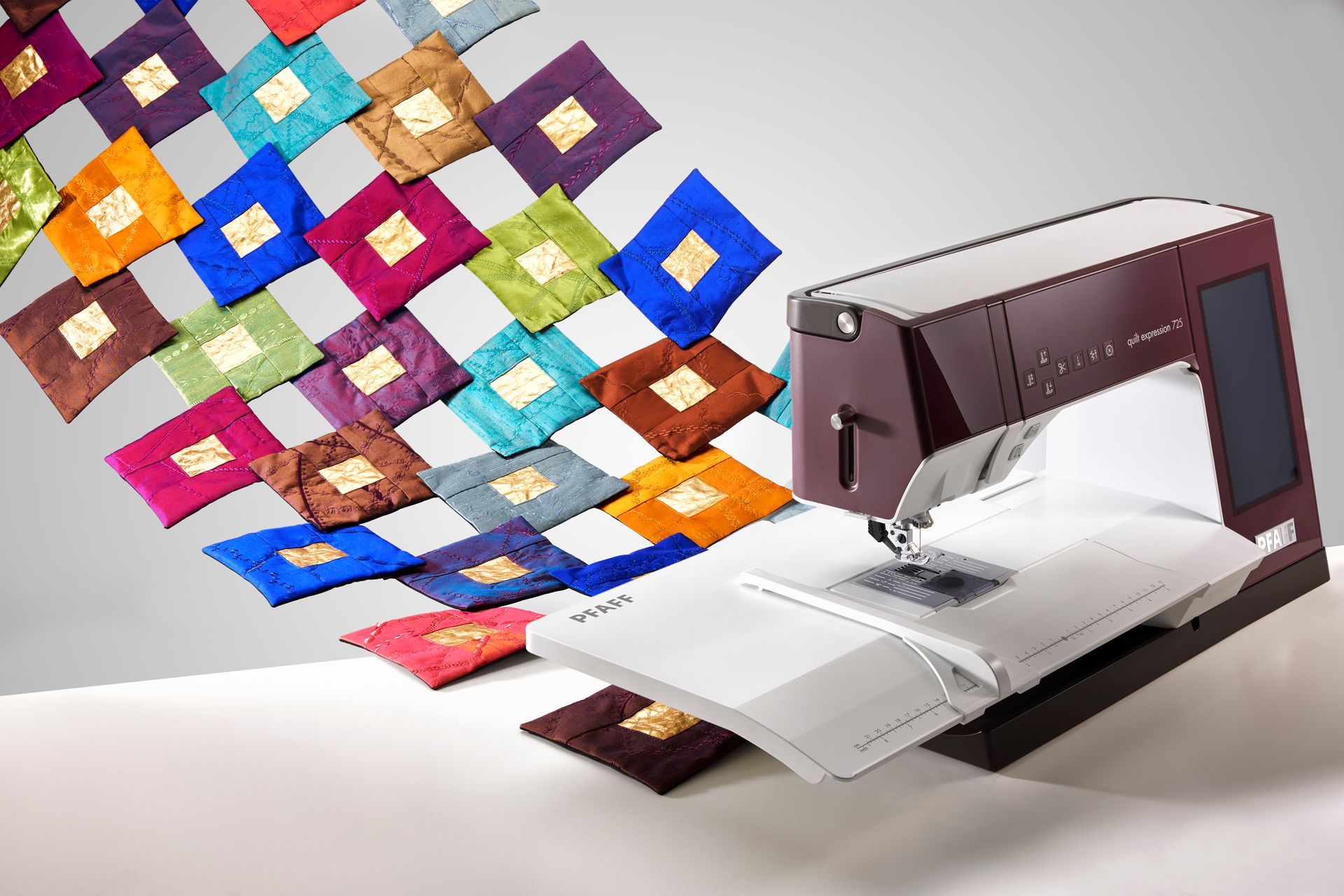 Sewing machine stitching a white fabric, with colorful patchwork squares flowing out beside it