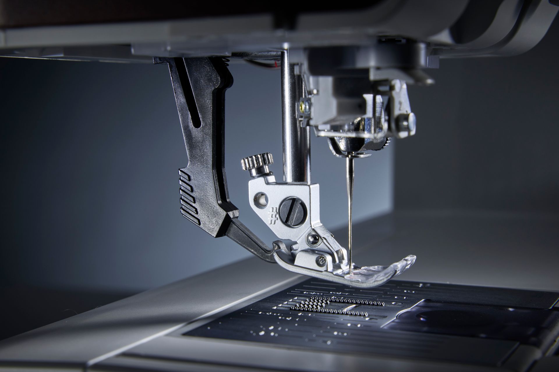 Close-up of a sewing machine stitching dark fabric under the needle